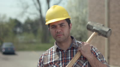 stock-footage-workman-wearing-hard-hat-and-holding-large-sledgehammer-ready-to-work-and-posing-for-camera.jpg